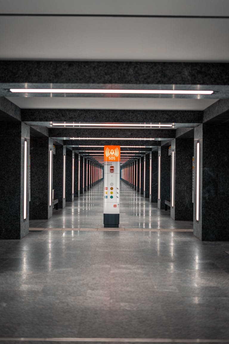 Symmetrical view of a modern subway hallway with an SOS post in the center.